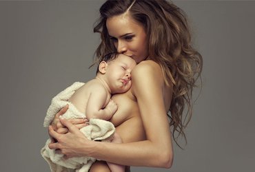 mommy makeover patient model holding her baby against her chest
