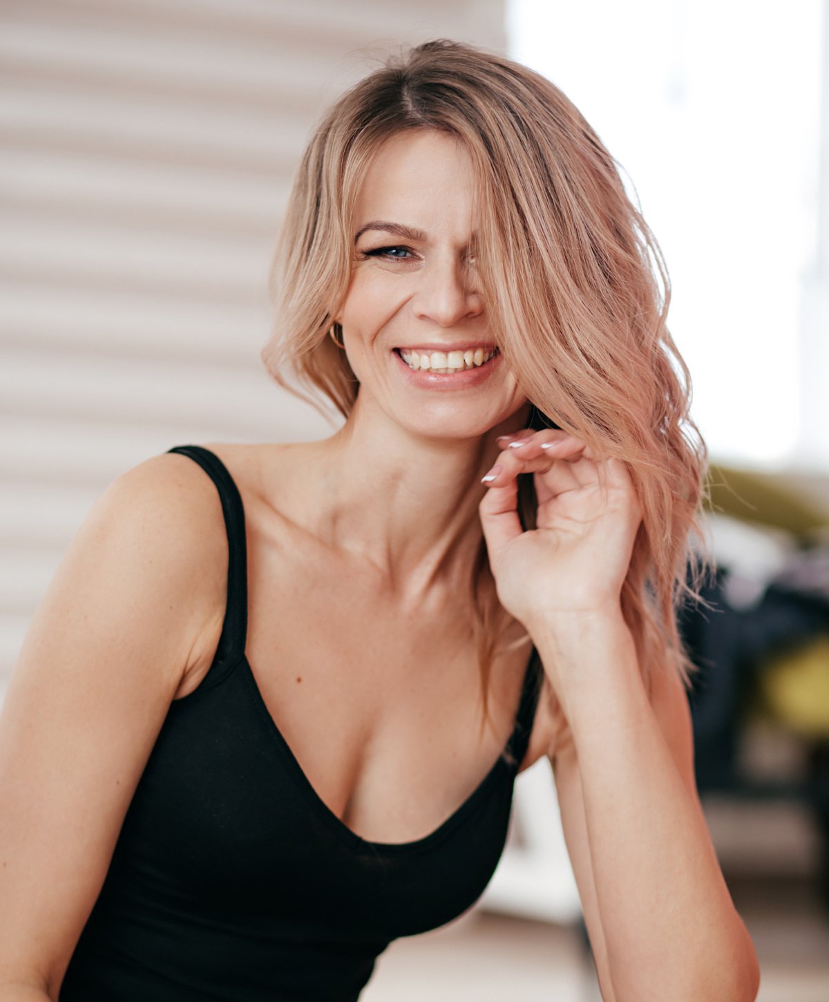 blepharoplasty patient model sitting in a chair smiling wearing a black tank top
