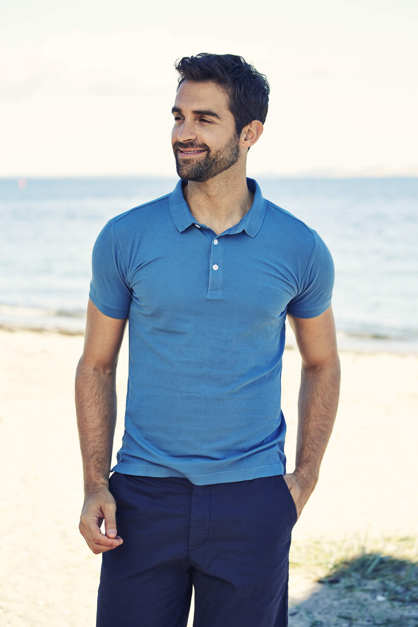Facelift and Neck Lift for Men patient model standing on a beach in a blue shirt