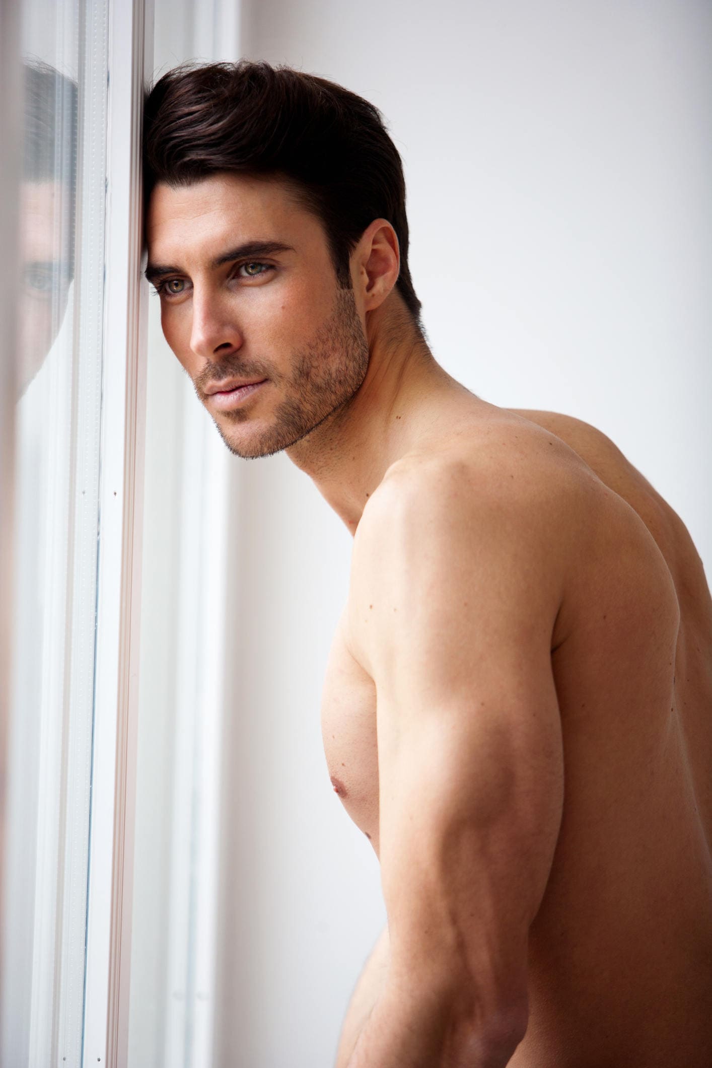 Facial Implants for Men patient model leaning his head against a window